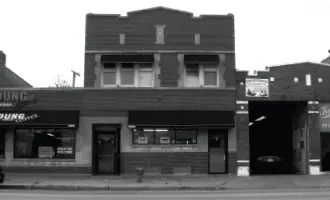 Black and white image of a two-story brick commercial building with an adjacent garage.