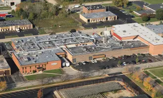 Aerial view of a complex with red brick buildings and flat, gray roofs