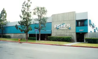A modern rectangular commercial building with teal and gray colors, featuring Fisher signage