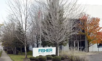 Commercial building with trees and a Fisher sign in front.