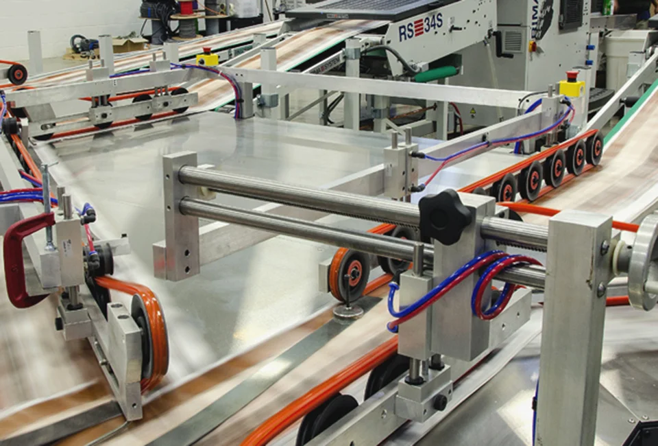 A fast-moving printing press with paper sheets, surrounded by metal rails and machinery.