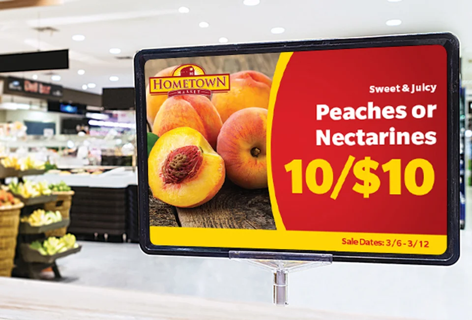 Promotional sign in a grocery store advertising peaches or nectarines at 10 for $10.